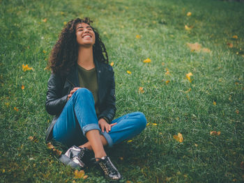 Cheerful young woman sitting on grass