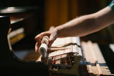 Cropped hands of man repairing piano