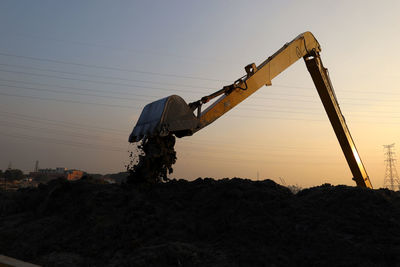 Low angle view of construction site against sky during sunset