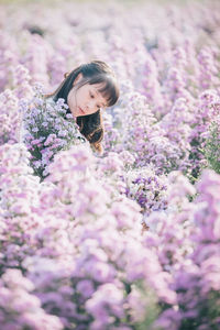 Beautiful woman standing by purple flowering plants