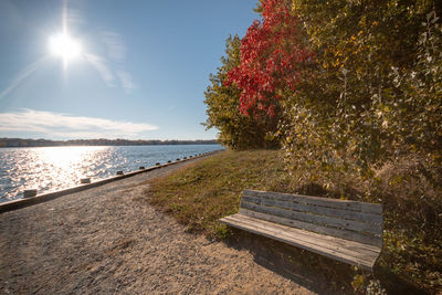 Bench by sea against sky