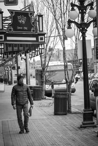 Rear view of man walking on sidewalk in city