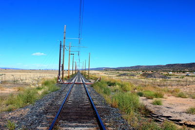 Railroad tracks against clear blue sky