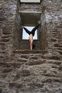 Young man exercising on stone wall