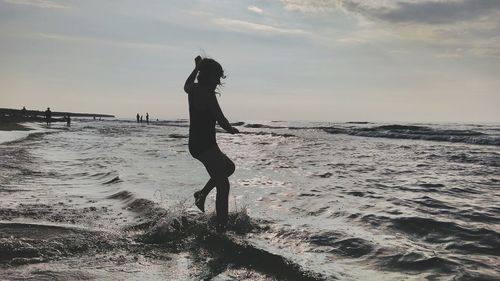 Full length of girl standing on beach against sky