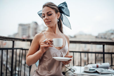 Young woman drinking coffee on railing