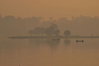 Silhouette of boat in calm sea at sunset