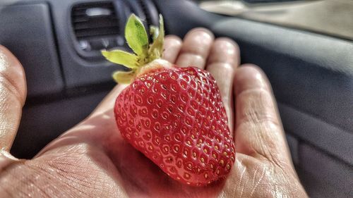 Close-up of hand holding strawberry in car