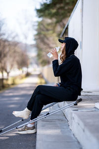 Young man using mobile phone while sitting on road