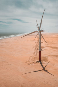 Windmills at beach against sky