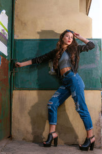 Full length of young woman standing against wall