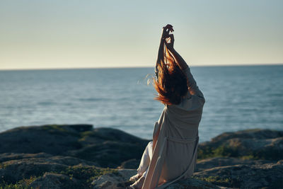 Woman with arms raised in sea against sky