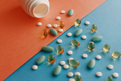 High angle view of pills spilling from bottle on yellow background