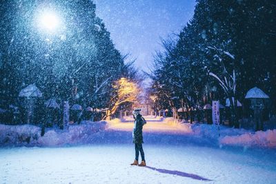 Man standing on snow covered street at night