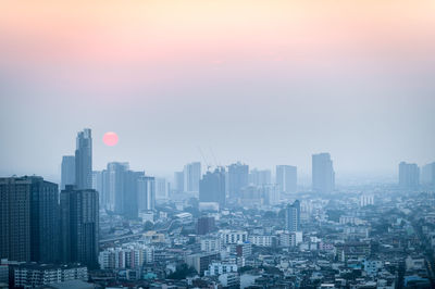 Aerial view of buildings in city at sunset