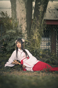 Young woman wearing traditional clothing while sitting on land
