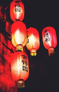 Low angle view of illuminated lanterns hanging against sky at night