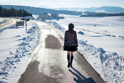 Rear view of woman standing on snow covered mountain