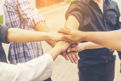 Close-up of friends stacking hands while huddling outdoors