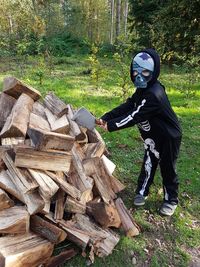 Full length of young woman standing on log in forest