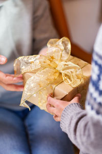 Closeup of hands of senior woman and a child holding a gift at christmas