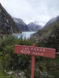 Information sign by mountains against sky