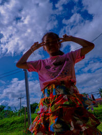 Low angle view of woman standing on field against sky