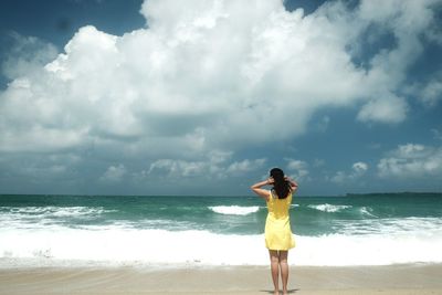 Woman standing on beach against sky