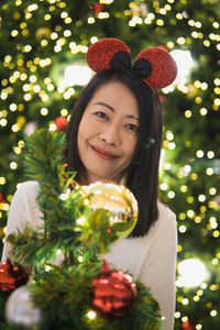 Portrait of young woman holding christmas tree