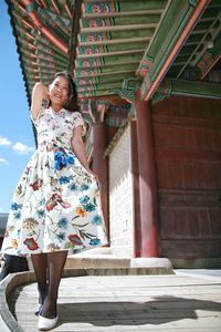 Full length portrait of young woman standing outside temple