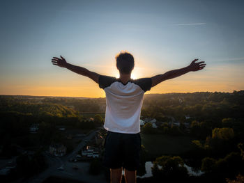 Rear view of man standing against sky at sunset