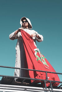 Low angle view of woman standing against clear blue sky