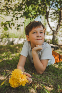 Portrait of smiling boy with yellow flowers on land