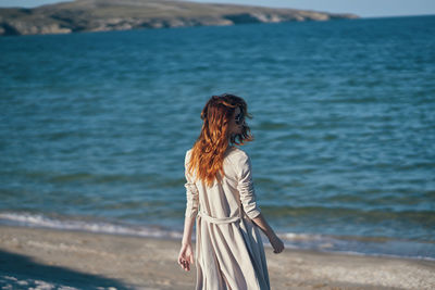 Rear view of woman standing at beach