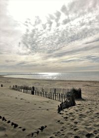 Wooden posts on beach against sky