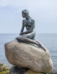 Statue by sea against sky