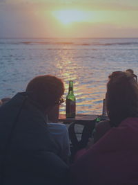 Rear view of people sitting on beach
