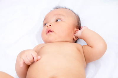 Close-up of naked baby boy lying on bed