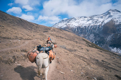 Man riding horse on mountain against sky