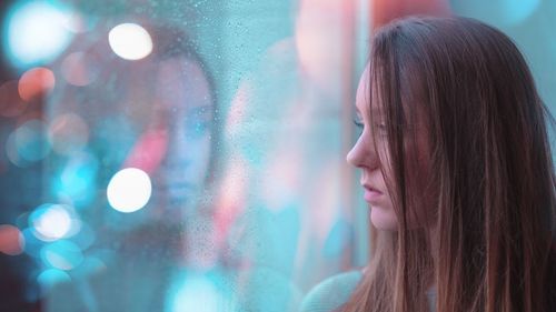 Woman looking at her reflection in glass window