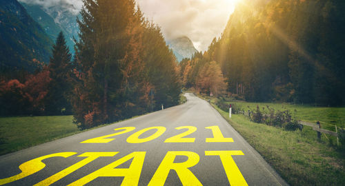 Road sign by trees against sky