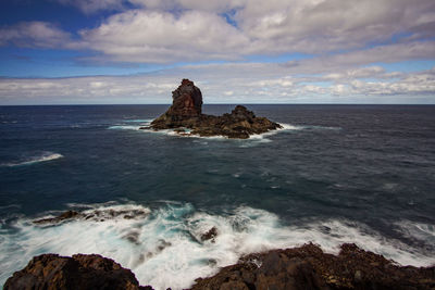 Rock formation on sea shore against sky
