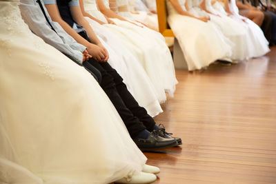 Low section of bridesmaids sitting at hardwood floor