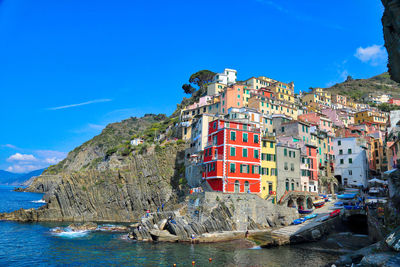 Buildings by mountain against blue sky