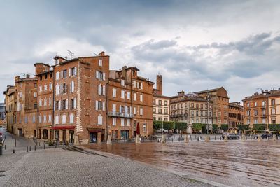 Buildings in city against cloudy sky