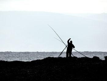 Rear view of man standing on beach against sky