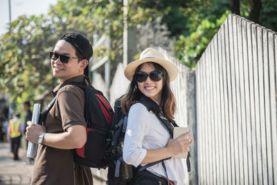 Smiling couple with backpacks traveling in city