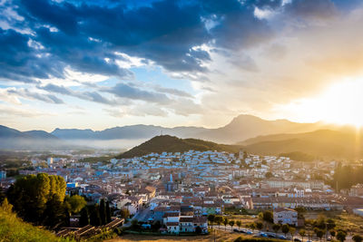 High angle view of townscape and mountains against cloudy sky