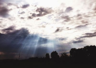 Low angle view of silhouette trees against cloudy sky