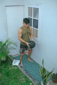 Full length of young man standing against wall at home